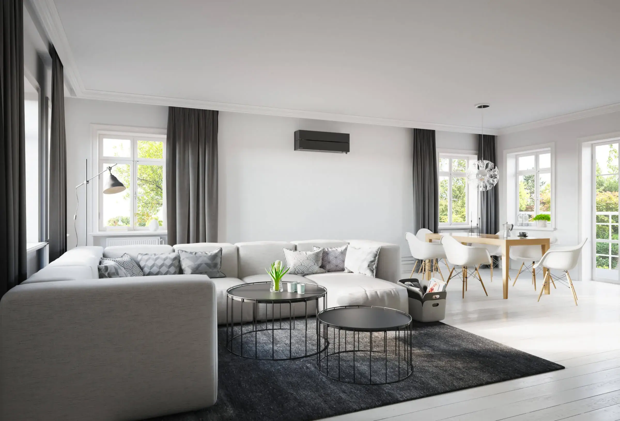 Vaalea kalustettu huone, jonka seinällä on musta ilmalämpöpumppu.